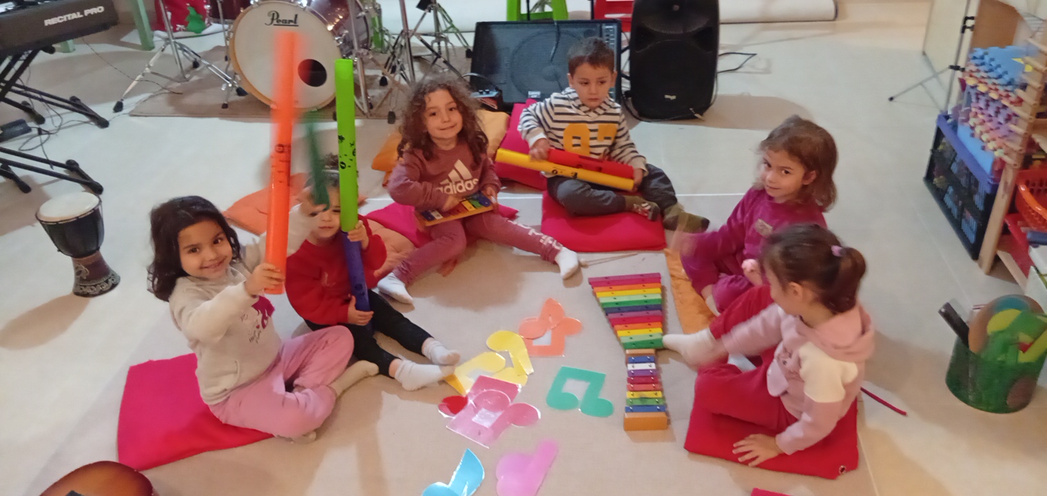 Παιδιά σε κύκλο με σωλήνες ήχου, μεταλλόφωνα και χρωματιστές νότες